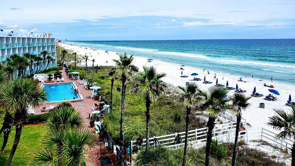 View looking down over Casa Loma and their pool and beach area on a sunny day with a bright blue ocean in Panama City, Florida, USA